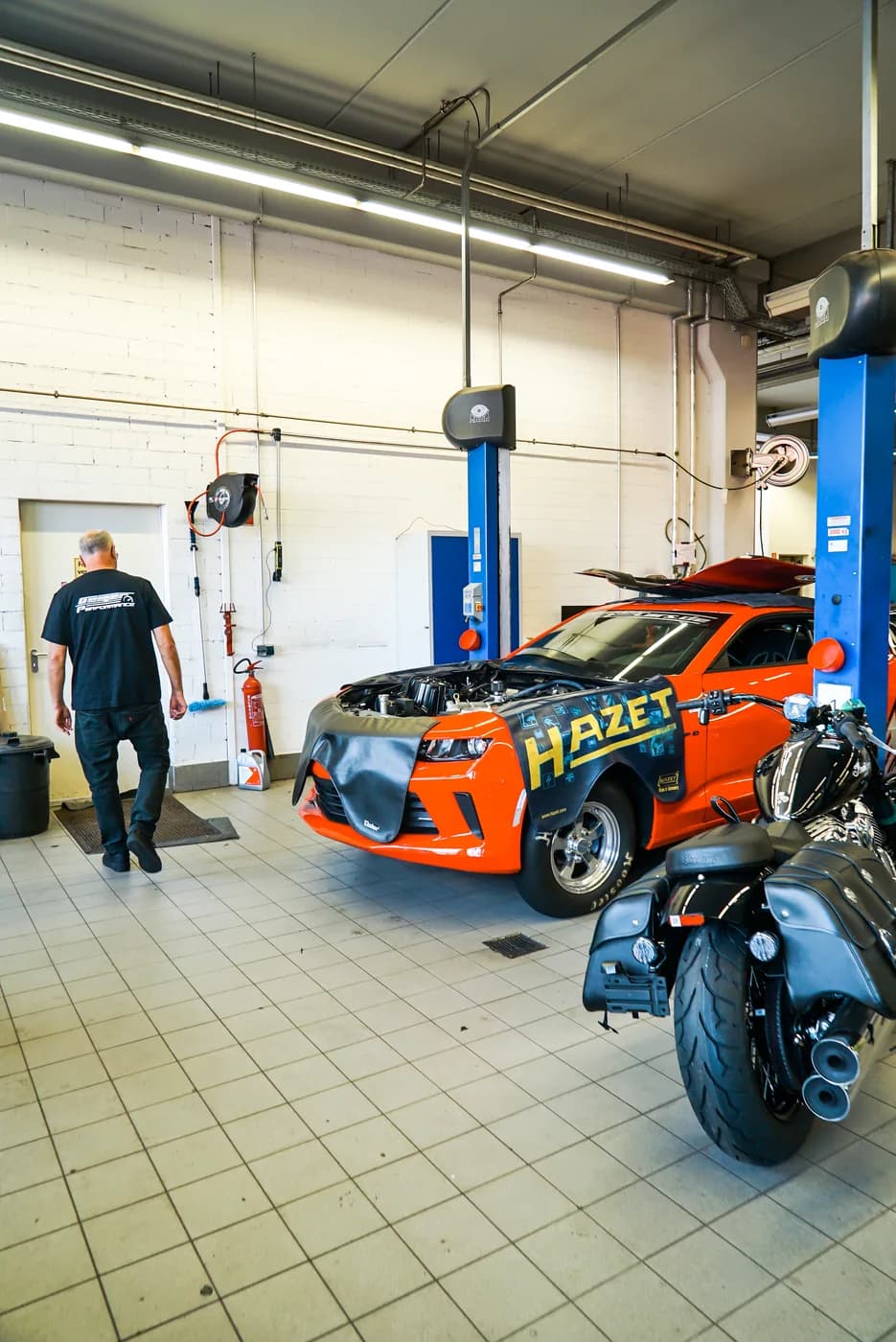 Mechanic in the GeigerCars workshop with a Camaro on the lift